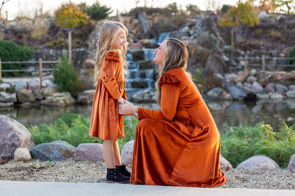 Mother and daughter looking at each other smiling in front of a waterfall